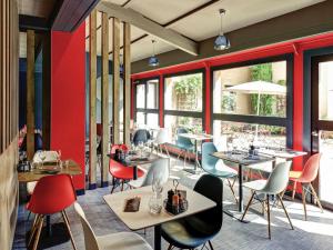 a restaurant with tables and chairs and windows at ibis Lyon Nord in Dardilly