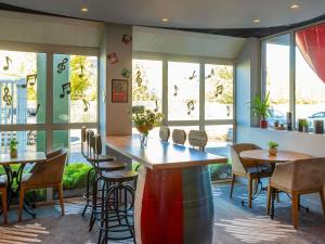 a restaurant with tables and chairs and windows at ibis Bordeaux Pessac Route des Vins in Pessac
