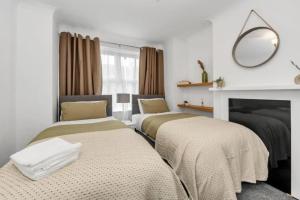 two beds in a room with a fireplace at Wherstead Rd House By Homestyles Hosts Short Lets & Serviced Accommodation Suffolk With Free Parking in Ipswich