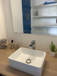 a white sink in a bathroom with a mirror at Diamant Bleu studio, piscine, vue mer in Le Diamant +19 photos
