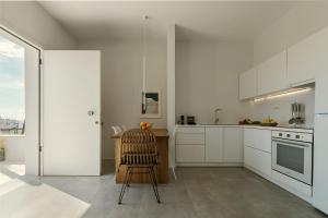 una cocina con armarios blancos y una silla. en AELIA Tinos, en Tinos