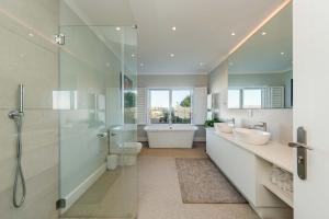 Villa Infinity Plettenberg Luxury Ocean View في بليتنبيرغ باي: حمام مع مغسلتين ودش وحوض استحمام +64 صورة