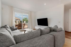 a living room with a gray couch and a television at Obsidian Olivino Miraverde in Adeje