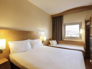a hotel room with two beds and a window at Ibis London Luton Airport in Luton +35 photos