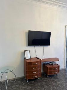 a room with a tv on a wall with a desk and a table at Трёхкомнатная квартира на Караменде-би in Balqash