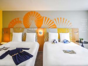 two beds in a room with umbrellas on the wall at Hôtel Mercure Lille Aéroport in Lesquin +189 photos