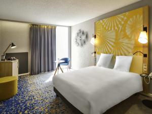 a hotel room with a large bed and a desk at Hôtel Mercure Lille Aéroport in Lesquin