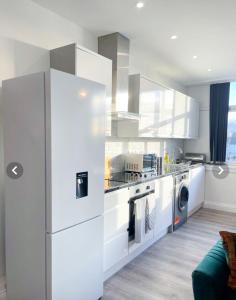 a white kitchen with a refrigerator and a dishwasher at The Felix Apartments in Flitwick