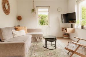 a living room with a couch and a table at Vakantiehuisje met ruime tuin en hottub in Ouddorp