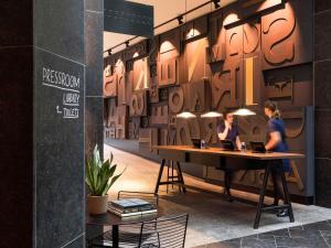 two women working at a table in a room with a wall with letters at INK Hotel Amsterdam - MGallery Collection in Amsterdam