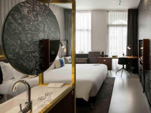 a hotel room with a bed and a large mirror at INK Hotel Amsterdam - MGallery Collection in Amsterdam