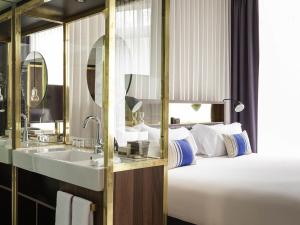 a hotel bathroom with a sink and a bed at INK Hotel Amsterdam - MGallery Collection in Amsterdam