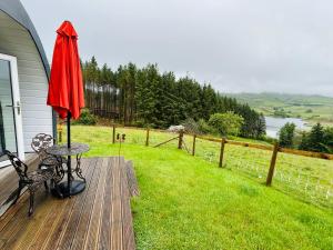 a patio with a table and an umbrella on a deck at Forester's Retreat Glamping - Dinas View - Dogs over the age of 2 with vaccination accepted RALI CEREDIGION EVENT 4TH-6TH SEP 2026 in Aberystwyth