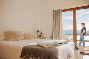 a man standing next to a bed in a room with a window at Del Lago Sky Hotel in San Carlos de Bariloche