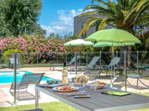 a table with plates of food and a green umbrella at Mercure Cannes Mandelieu in Cannes