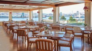 un restaurant avec des tables et des chaises et une vue sur l'eau dans l'établissement NH Collection A Coruña Finisterre, à La Corogne