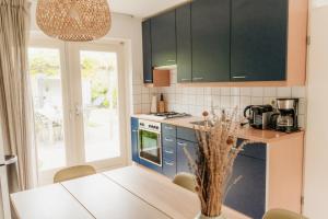 a kitchen with blue cabinets and a table at Vakantiehuisje met ruime tuin en hottub in Ouddorp