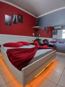 a bedroom with a large bed with red walls at Motel A 2 in Criciúma +4 photos