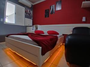 a bedroom with a bed with red walls and a chair at Motel A 2 in Criciúma +7 photos