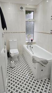 Un baño blanco con bañera y inodoro. en Cosy 2 bedroom flat, en Edgware 2 fotos más