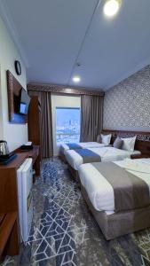 a hotel room with three beds and a large window at فندق البارون الذهبي in Az Zāhir