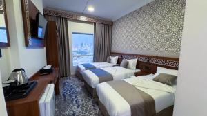 a hotel room with two beds and a window at فندق البارون الذهبي in Az Zāhir
