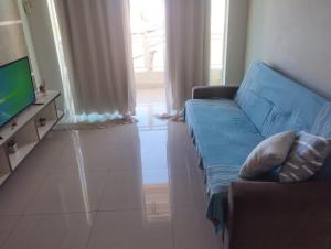a living room with a blue couch and a television at Apartamento 200 metros da praia e próximo a comércios in Rio das Ostras
