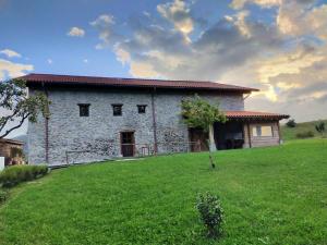 a large stone building on a grassy hill at Gautegiz Arteaga Reserva Urdaibai in Isla Becoa