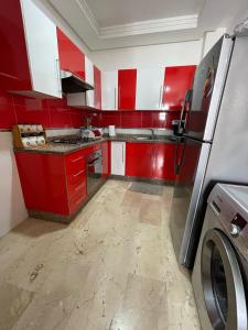 a red and white kitchen with a washing machine in it at Résidence Ryad Albahr Herhoura in Temara
