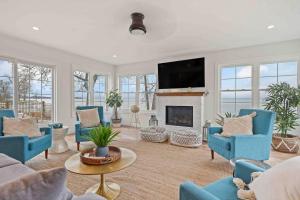 een woonkamer met blauwe stoelen en een open haard bij Crystal Beach Executive Waterfront Lakehouse in Crystal Beach
