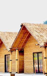 a wooden house with a straw roof at Bliss Hampi Eco Resort in Hampi