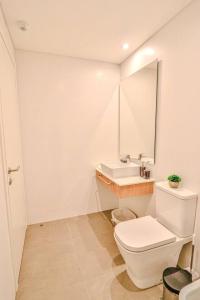 a white bathroom with a toilet and a sink at Stylish Retreat Steps from Shopping del Sol in Asuncion