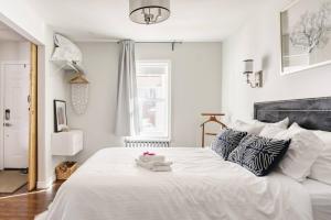 Schlafzimmer mit einem großen weißen Bett mit einem schwarzen Kopfteil in der Unterkunft Wood-Rich Niagara Loft close to Queen Street in Niagara Falls
