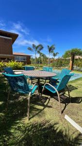a picnic table with blue chairs and a pool at Reserva dos jacarandás praia do forte in Praia do Forte