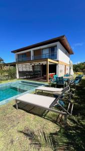 a house with a pool and some chairs in front of it at Reserva dos jacarandás praia do forte in Praia do Forte