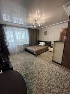 a bedroom with a bed and a chandelier at Апартаменты на СОВЕТСКОЙ 39 in Petropavlovsk