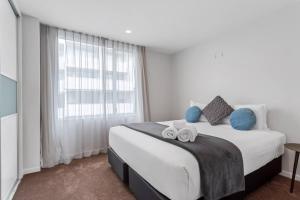 een slaapkamer met een groot wit bed met blauwe kussens bij QV Stays Modern Spacious Multi-Level Townhouse in Auckland