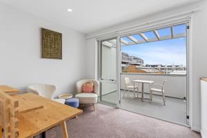 een kamer met een tafel en stoelen en een balkon bij QV Stays Modern Spacious Multi-Level Townhouse in Auckland