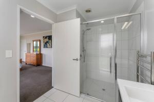 ein weißes Badezimmer mit Dusche und Waschbecken in der Unterkunft Family fun at Wharewaka in Taupo Airport + 19 Fotos