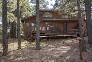 ein Blockhaus mit einer großen Terrasse im Wald in der Unterkunft 3BR Flagstaff Escape with Deck and Pine Views in East Flagstaff