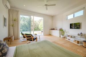 a bedroom with a bed and a living room with windows at Ideally Located Modern Studio Apartment in Dunsborough
