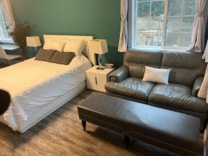 a bedroom with a bed and a leather couch at Ellison Funny Farm in Barrière