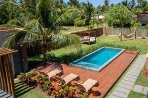 a backyard with a pool and a deck with chairs and a palm tree at Kokoye Boutique Hotel in Pôrto de Pedras