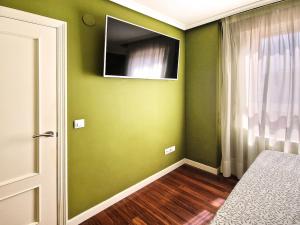 a bedroom with green walls and a television on the wall at Apartamento, zona residencia con piscina, cerca de las playas en Santander in Santander