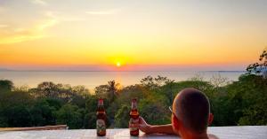 MéridaVilla Ometepe的一名男子坐在桌子上，手里拿着两瓶啤酒