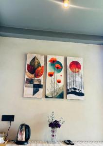 quatre peintures de feuilles sur un mur dans l'établissement Camellia Lodge Ella, à Ella