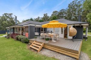 a house with a deck with a yellow umbrella at The Pond House Trentham in Trentham