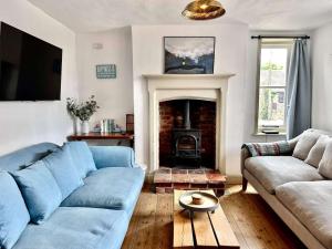ein Wohnzimmer mit einer blauen Couch und einem Kamin in der Unterkunft IVY COTTAGE - Walsingham in Little Walsingham