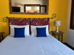 a bedroom with a white bed with blue pillows at Pousada Sabledor in Búzios