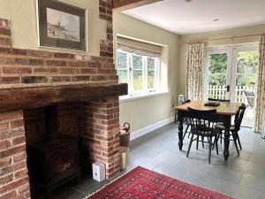 a living room with a brick fireplace and a dining room table at Plum Tree Cottage, Burnham Market By Together Travel in Burnham Market